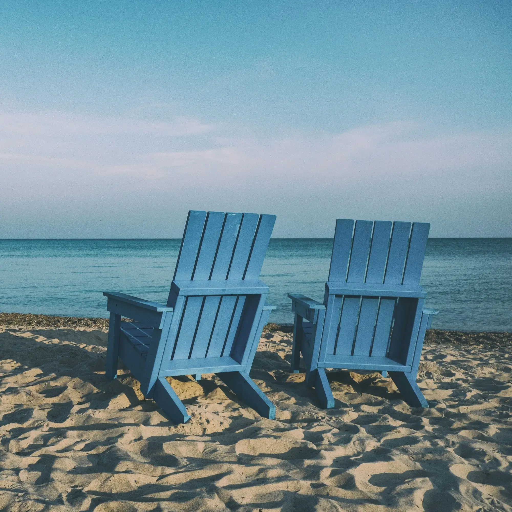 Two blue chairs sitting on the beach to symbolize retirement